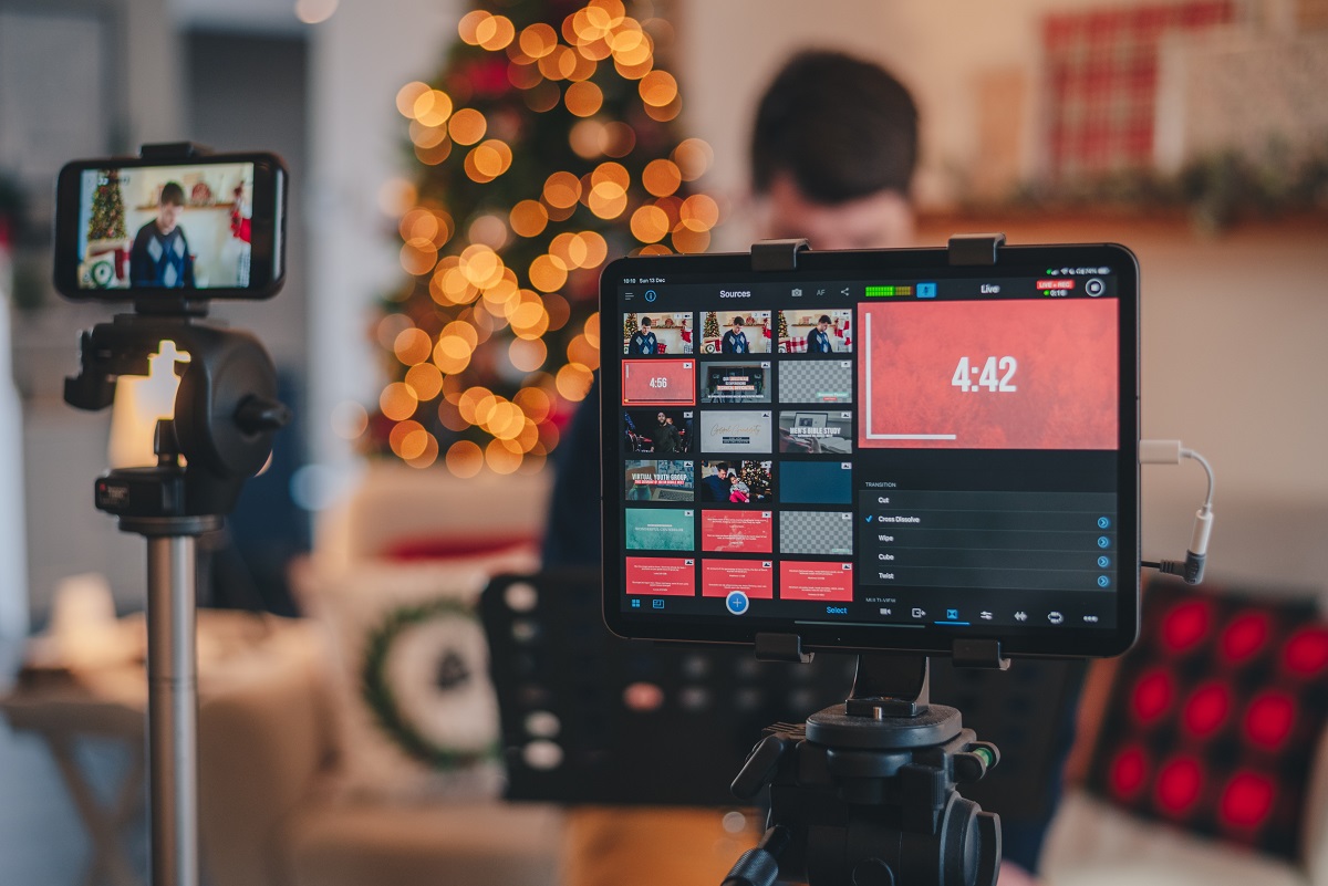 Criação de conteúdo em vídeo de Natal: homem está atrás de uma câmera. Ao fundo, um árvore de natal.